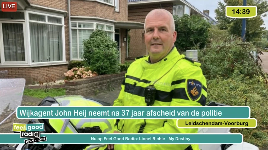 Tv-scherm met nieuwsbeeld, titel, plaatsnaam, klok en muziekinformatie